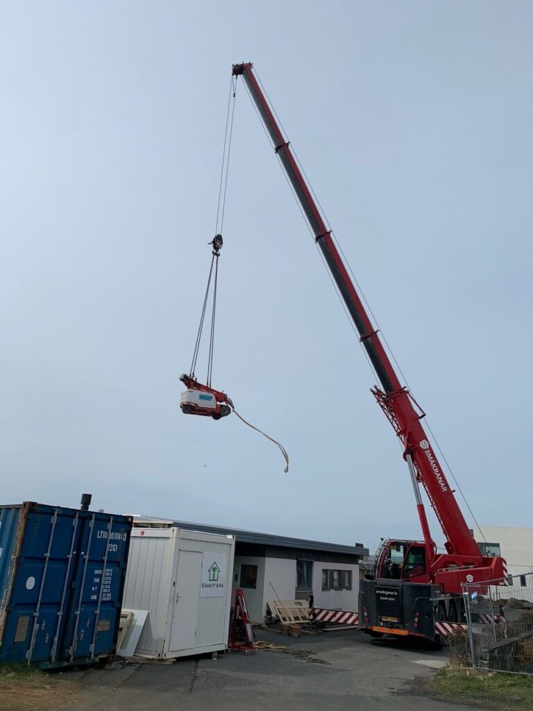 Bílkraninn hífir keyrslukranann yfir húsið